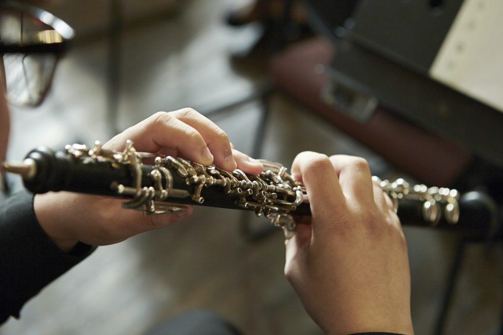 A closeup of a person playing the oboe, a preparatory instrument to the bassoon.