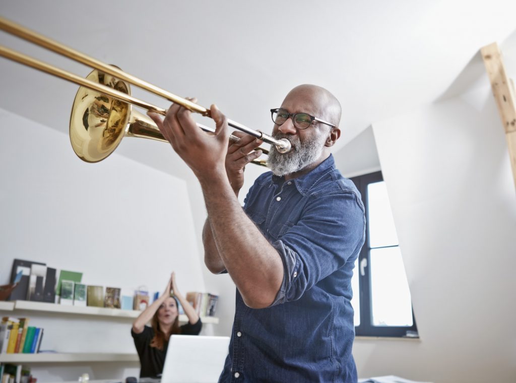 A man playing trombone after learning the trumpet, a preparatory instrument.
