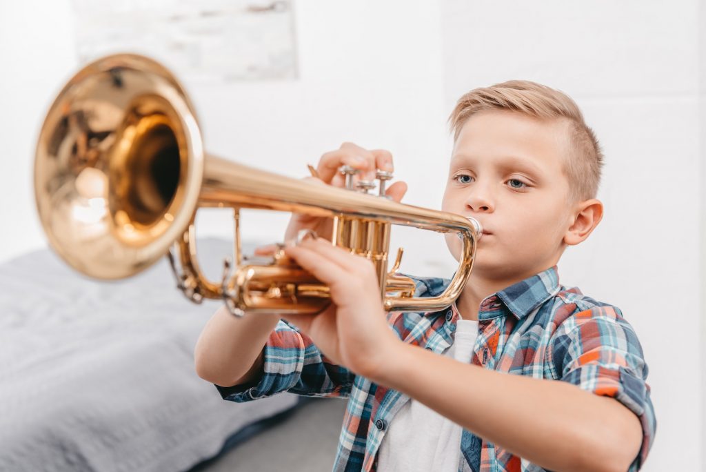 A boy playing trumpet as a preparatory instrument to other low brass instruments.
